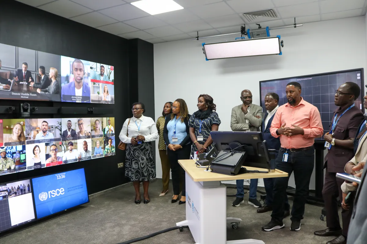 A group of people look at multiple TV screens with video conference calls displaying